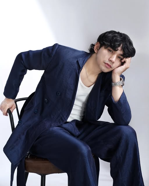 Editorial portrait of Ekhsan seated in a navy suit